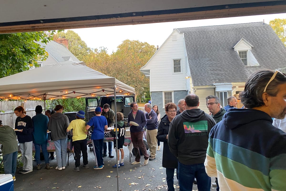 Guests lined up under the catering tent in the driveway at the BBQ